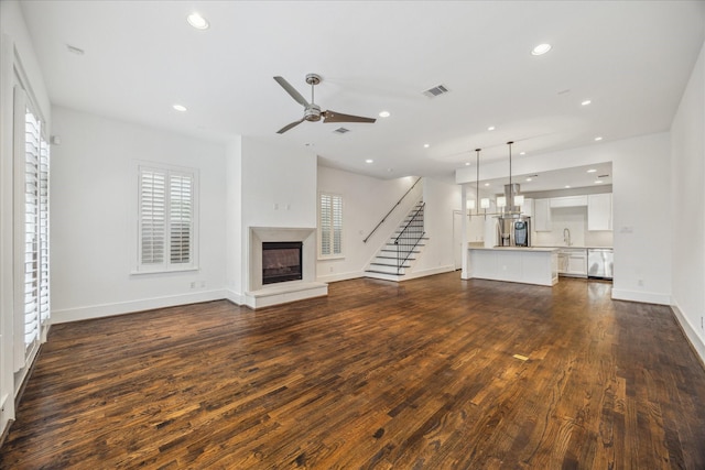 unfurnished living room featuring ceiling fan, sink, and dark hardwood / wood-style flooring