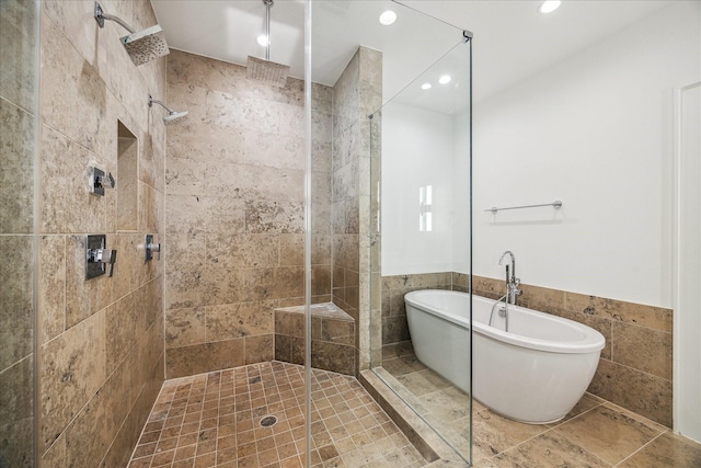 bathroom featuring plus walk in shower and tile walls