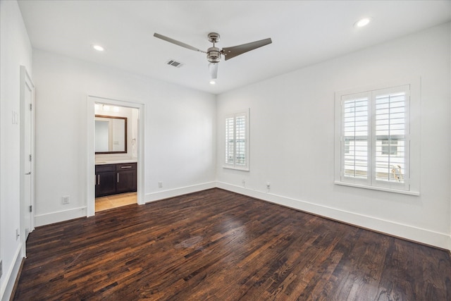 unfurnished bedroom with ceiling fan, ensuite bathroom, and dark hardwood / wood-style flooring