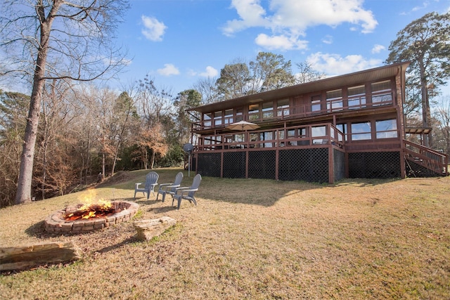 back of house with stairway, a fire pit, a deck, and a lawn