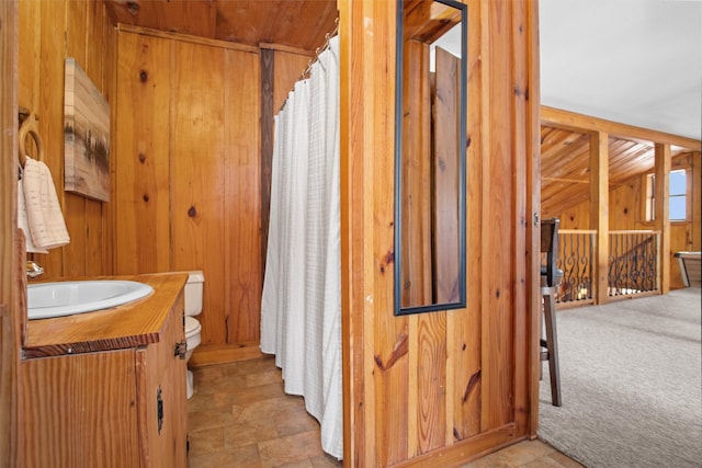 full bathroom with toilet, vanity, and wooden walls