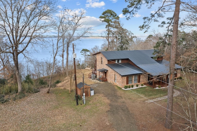 exterior space featuring driveway, a front lawn, metal roof, and brick siding