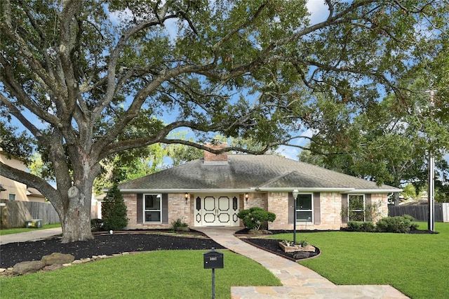 ranch-style house with fence, driveway, roof with shingles, a chimney, and a front yard