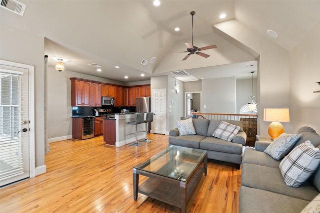 living room featuring high vaulted ceiling, light hardwood / wood-style floors, beverage cooler, and ceiling fan