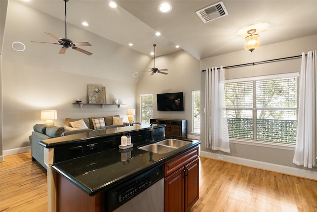 kitchen featuring dishwasher, lofted ceiling, sink, a center island with sink, and light wood-type flooring