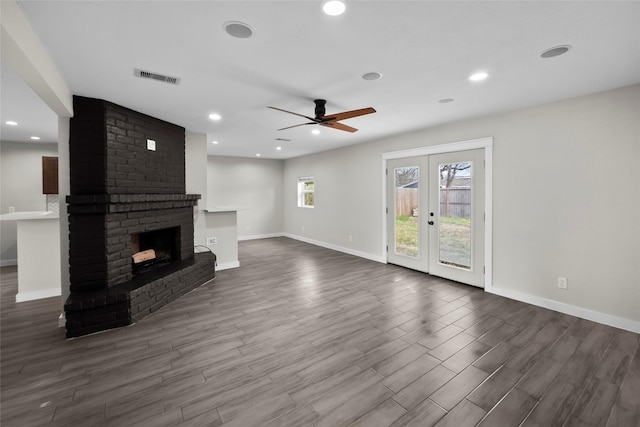 unfurnished living room with hardwood / wood-style flooring, a fireplace, french doors, and ceiling fan