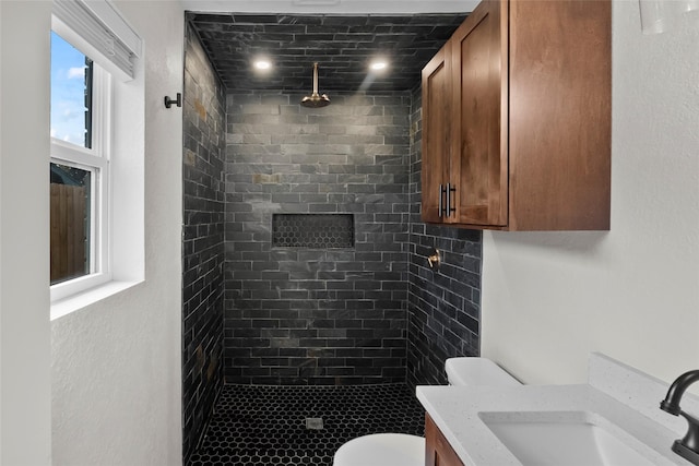 bathroom featuring tiled shower, vanity, and toilet