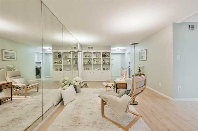 living room featuring washer / dryer and light hardwood / wood-style flooring