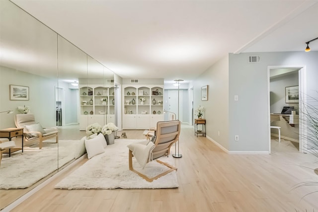 living room with built in shelves and light hardwood / wood-style floors