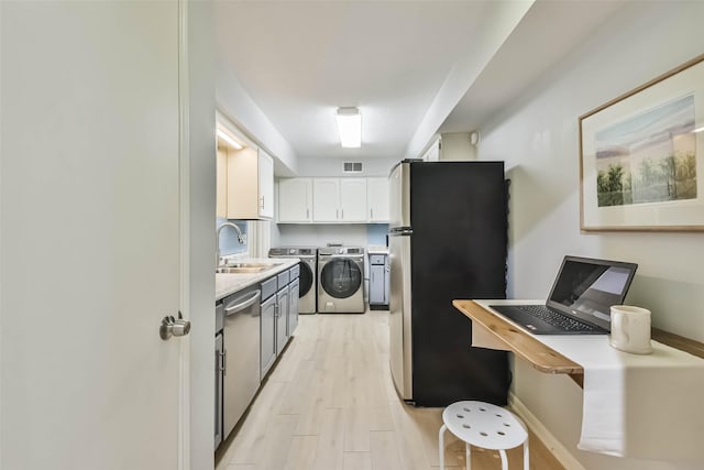 kitchen featuring separate washer and dryer, sink, white cabinets, stainless steel appliances, and light wood-type flooring