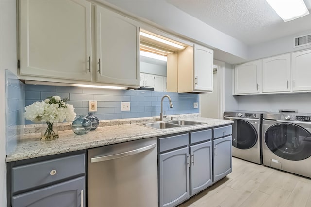 clothes washing area featuring sink, washing machine and dryer, light hardwood / wood-style floors, and a textured ceiling