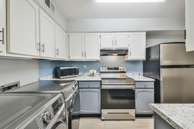 kitchen with white cabinetry, gray cabinetry, stainless steel appliances, tasteful backsplash, and light wood-type flooring