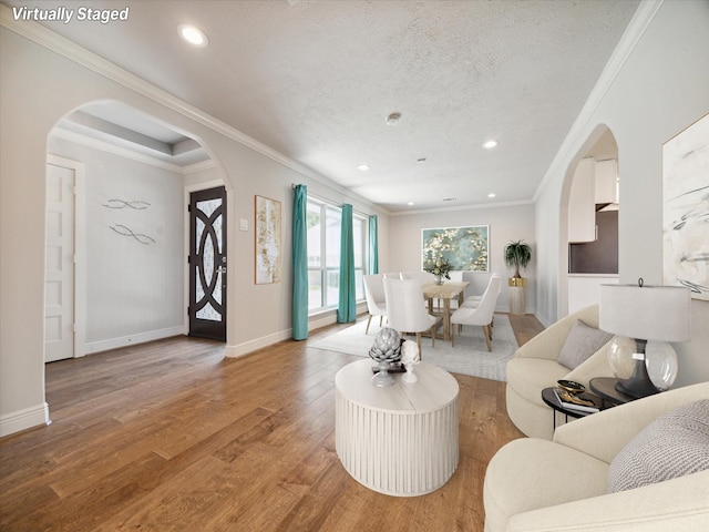 living room featuring ornamental molding, light hardwood / wood-style flooring, and a textured ceiling