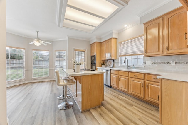 kitchen featuring dishwasher, sink, a breakfast bar area, decorative backsplash, and a center island