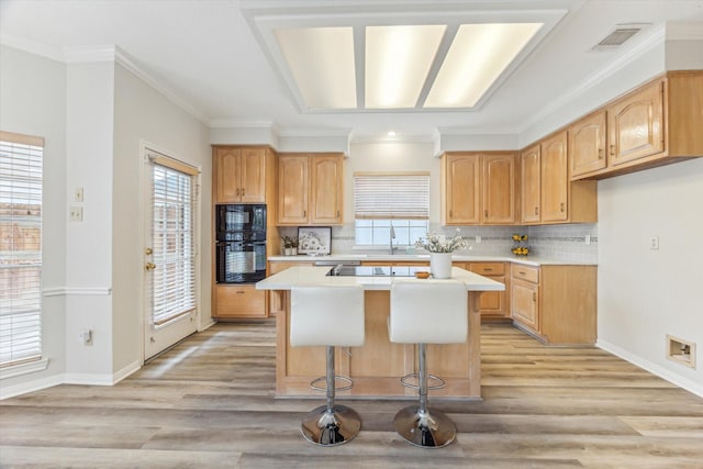 kitchen with a breakfast bar, sink, a kitchen island, light hardwood / wood-style floors, and black appliances