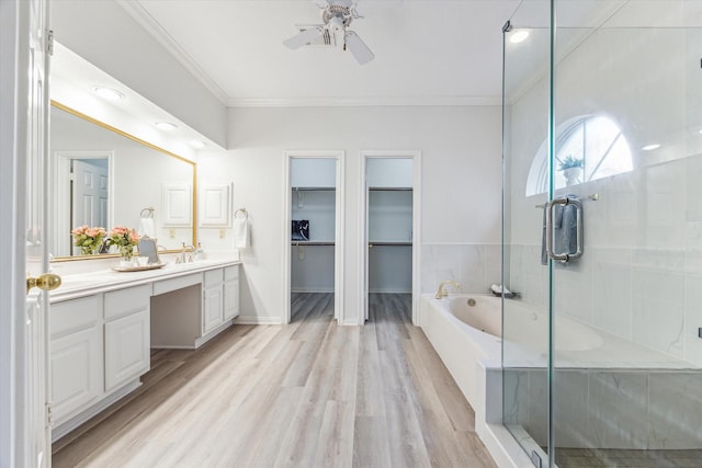 bathroom featuring independent shower and bath, hardwood / wood-style flooring, ornamental molding, vanity, and ceiling fan