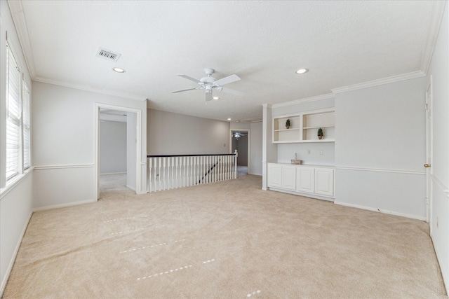 empty room featuring crown molding, light carpet, and ceiling fan