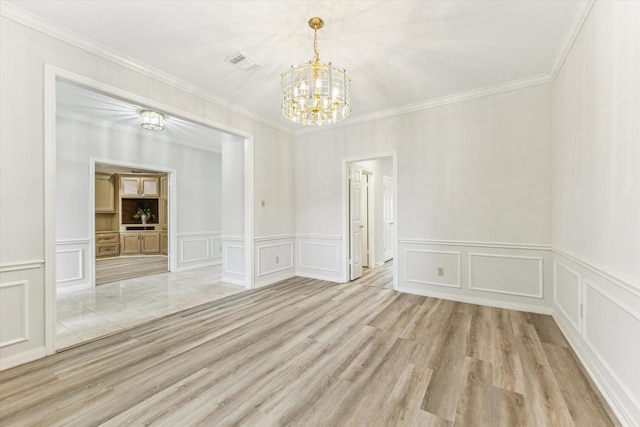 unfurnished room featuring ornamental molding, a chandelier, and light hardwood / wood-style flooring