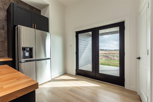 kitchen with butcher block countertops, light hardwood / wood-style floors, french doors, and stainless steel refrigerator with ice dispenser