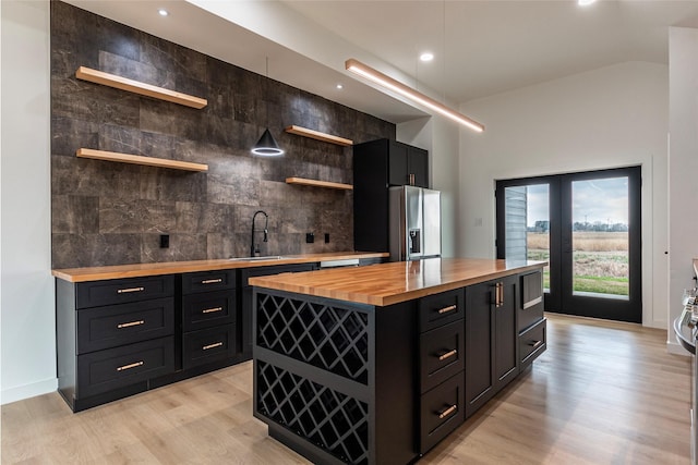 kitchen with sink, a center island, light hardwood / wood-style floors, wood counters, and stainless steel fridge with ice dispenser