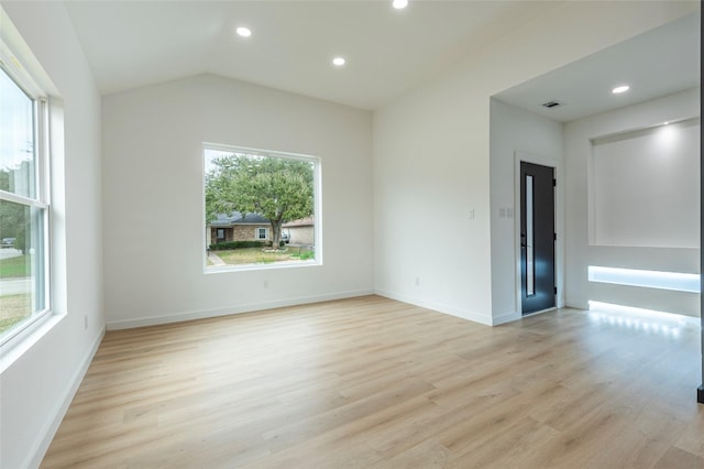 spare room with lofted ceiling and light hardwood / wood-style flooring