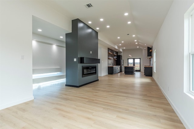 unfurnished living room with vaulted ceiling, a fireplace, and light hardwood / wood-style flooring