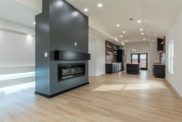 unfurnished living room featuring vaulted ceiling, sink, a fireplace, and light hardwood / wood-style flooring