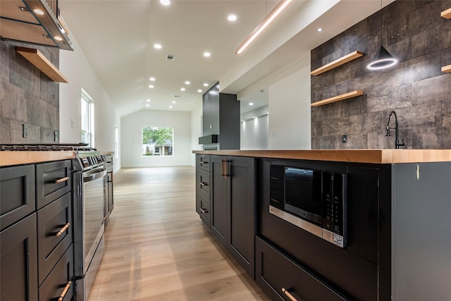 kitchen with tasteful backsplash, lofted ceiling, sink, stainless steel appliances, and light wood-type flooring