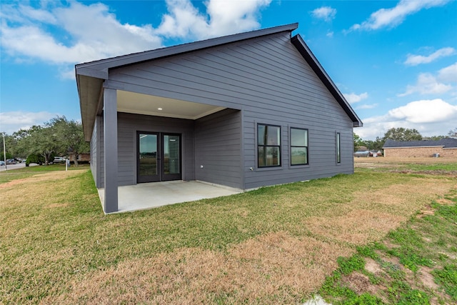 rear view of house featuring a patio, a lawn, and french doors