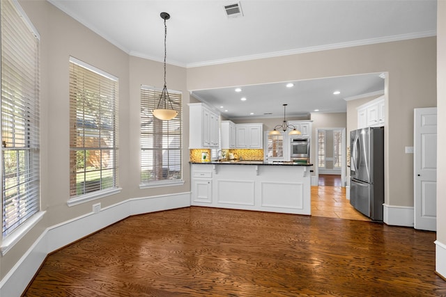 kitchen with crown molding, stainless steel fridge, hanging light fixtures, dark hardwood / wood-style floors, and white cabinets