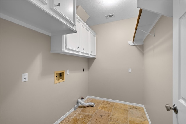 washroom with hookup for a gas dryer, hookup for a washing machine, a textured ceiling, and cabinets