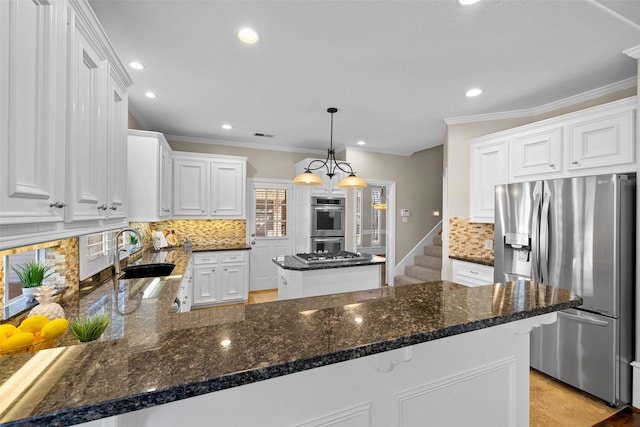 kitchen featuring appliances with stainless steel finishes, white cabinetry, sink, hanging light fixtures, and a center island