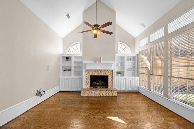 unfurnished living room with a tiled fireplace, wood-type flooring, and plenty of natural light