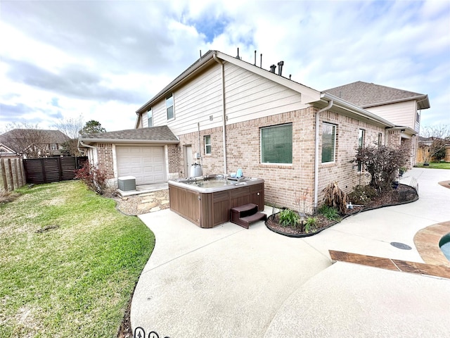 back of house featuring cooling unit, a fenced backyard, brick siding, a yard, and a hot tub