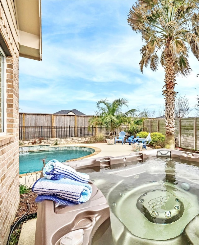 view of swimming pool with a hot tub and a fenced backyard