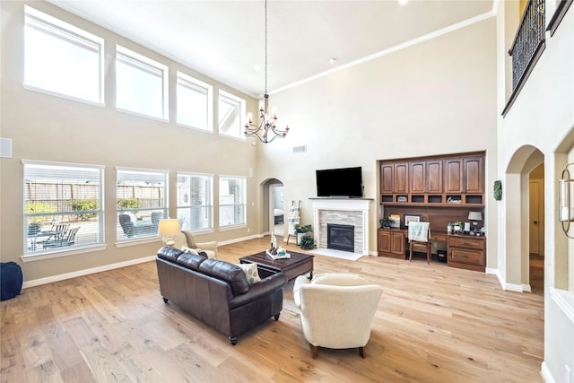 living room with crown molding, a high ceiling, a notable chandelier, arched walkways, and light wood-style flooring