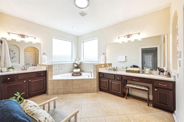 bathroom featuring a garden tub, tile patterned flooring, visible vents, and a sink