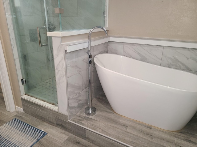 bathroom with shower with separate bathtub and tile walls