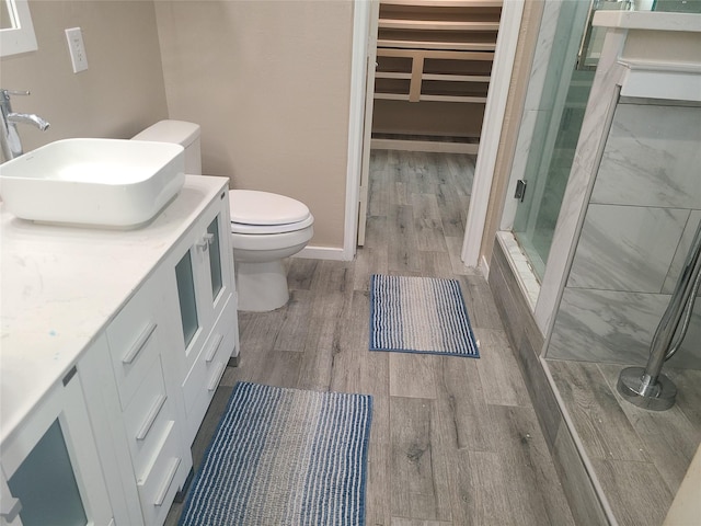 bathroom featuring hardwood / wood-style flooring, vanity, an enclosed shower, and toilet