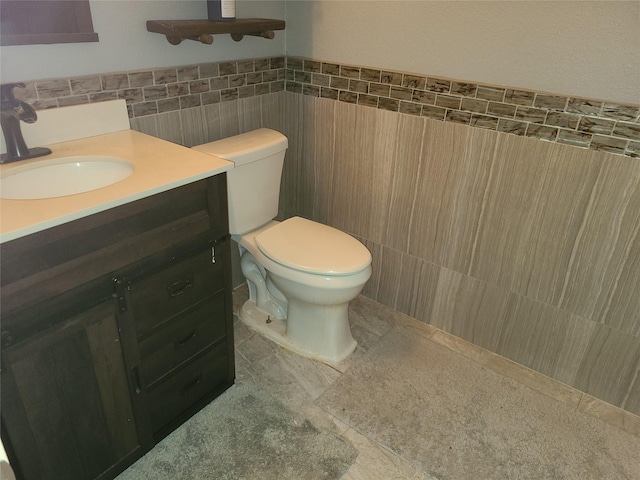 bathroom featuring tile patterned flooring, vanity, tile walls, and toilet