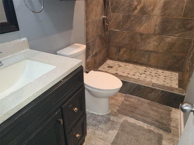 bathroom with vanity, a tile shower, and toilet