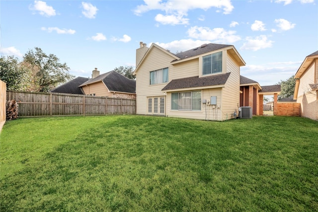 rear view of house featuring central AC and a lawn