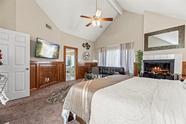 carpeted bedroom featuring ensuite bath, high vaulted ceiling, beamed ceiling, ceiling fan, and a fireplace