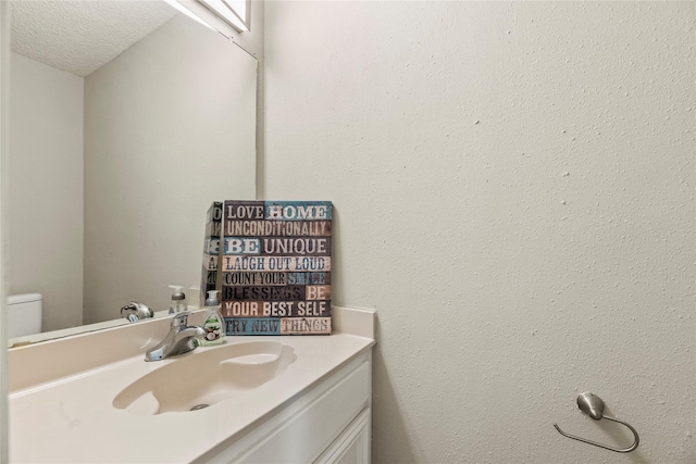 bathroom with vanity, a textured ceiling, and toilet