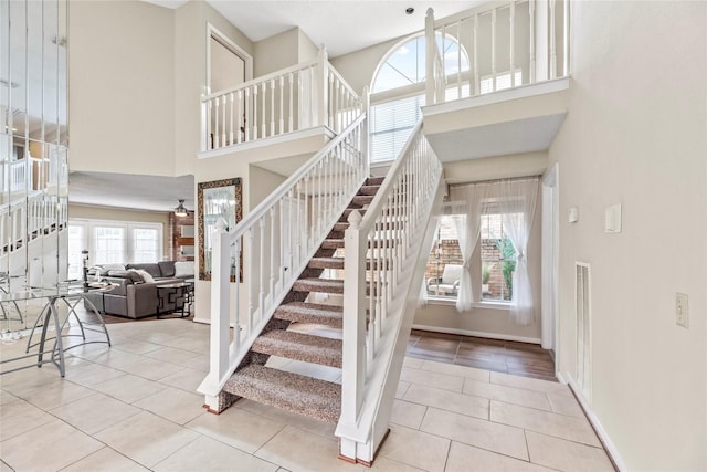 staircase with tile patterned flooring, a towering ceiling, and ceiling fan