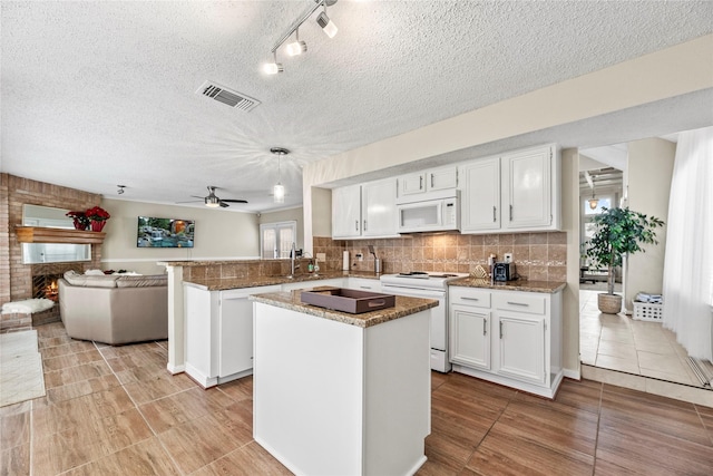 kitchen featuring white cabinetry, white appliances, a fireplace, and kitchen peninsula