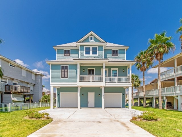 beach home featuring a front yard, fence, and an attached garage