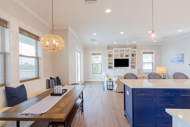 kitchen with a healthy amount of sunlight, light wood-style flooring, light countertops, and crown molding