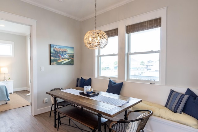 dining space with baseboards, a notable chandelier, light wood-style flooring, and crown molding