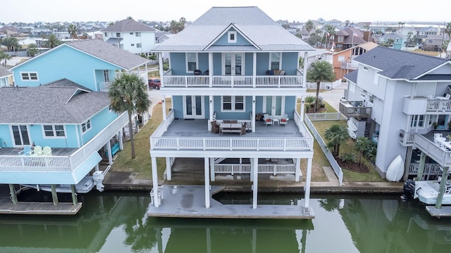 rear view of property with a residential view, french doors, a water view, and a balcony